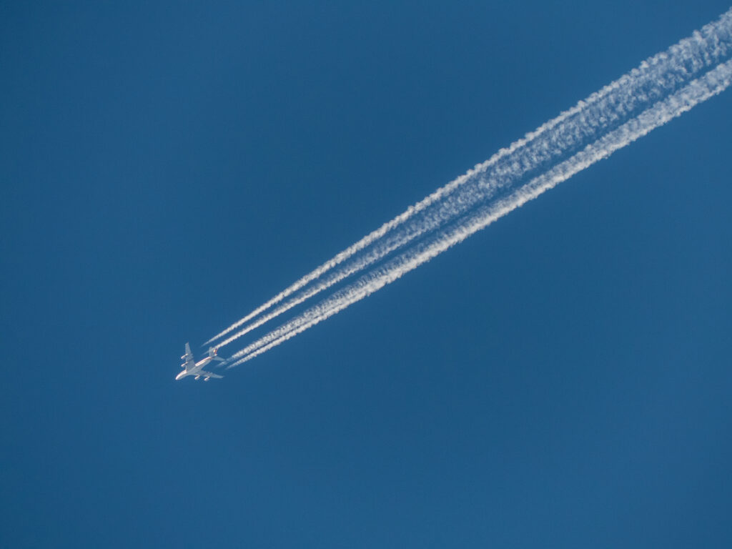 A long-haul airliner in flight leaving condensation trails across the sky
