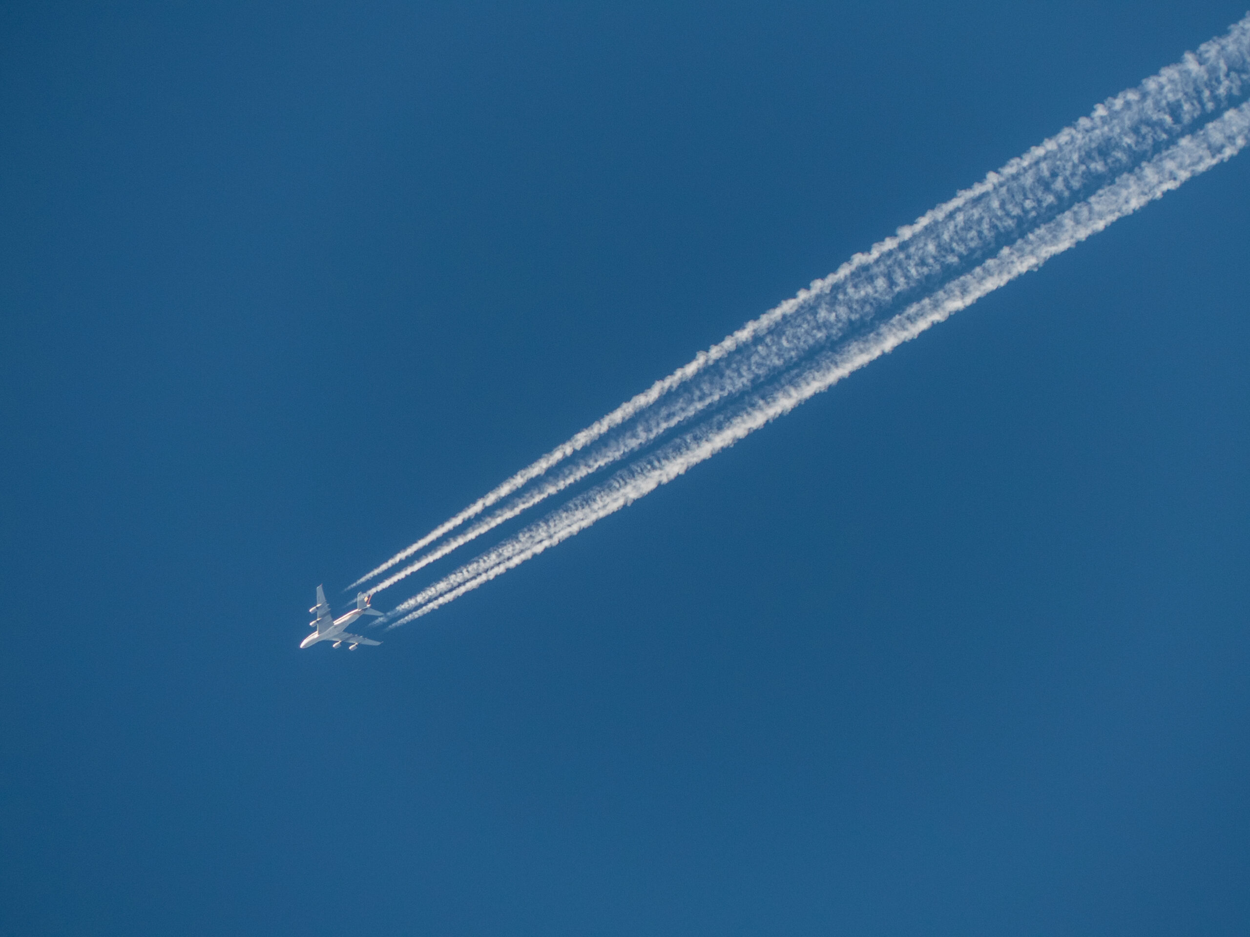 A long-haul airliner in flight leaving condensation trails across the sky